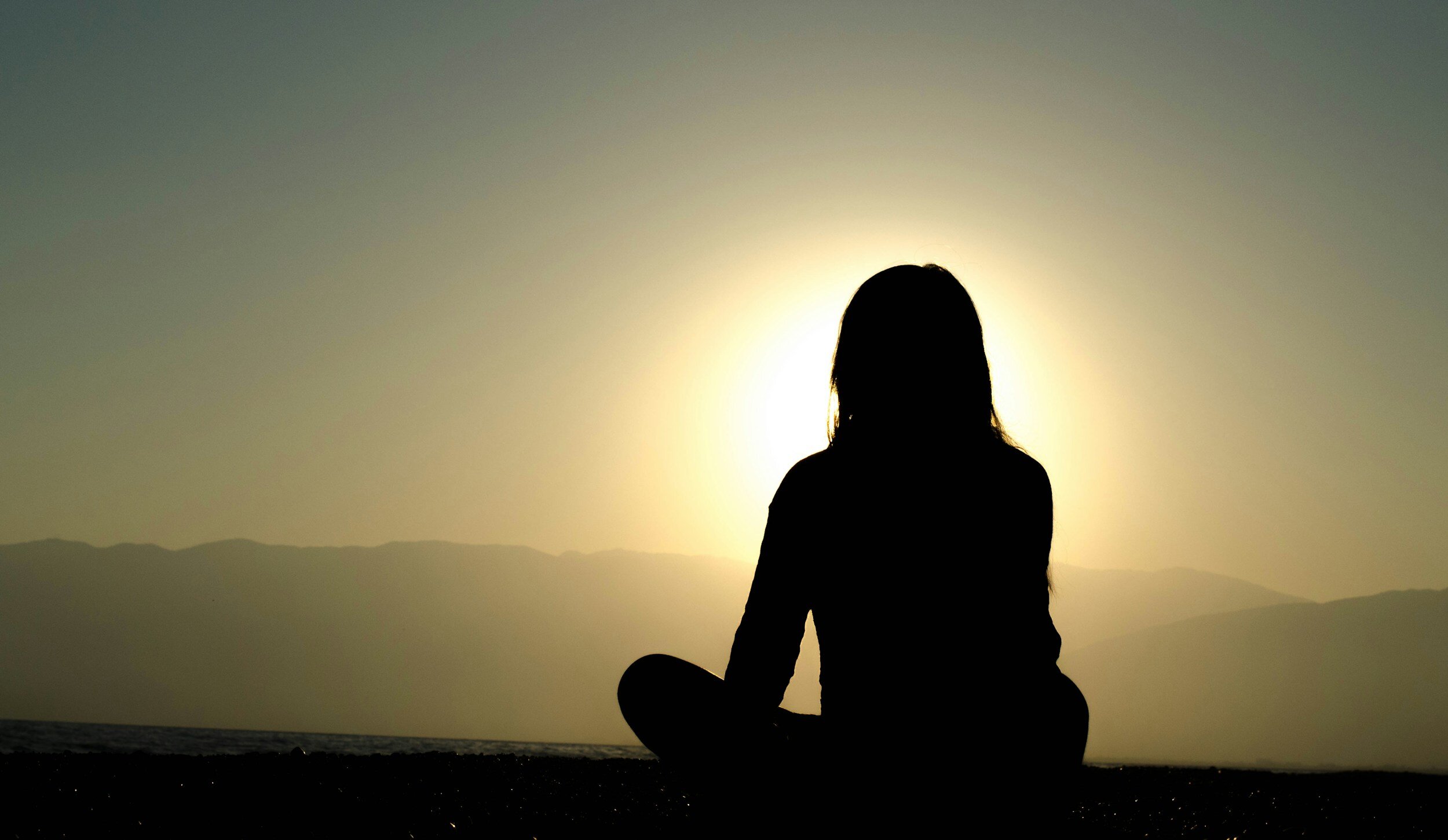 woman meditating in front of the Sun